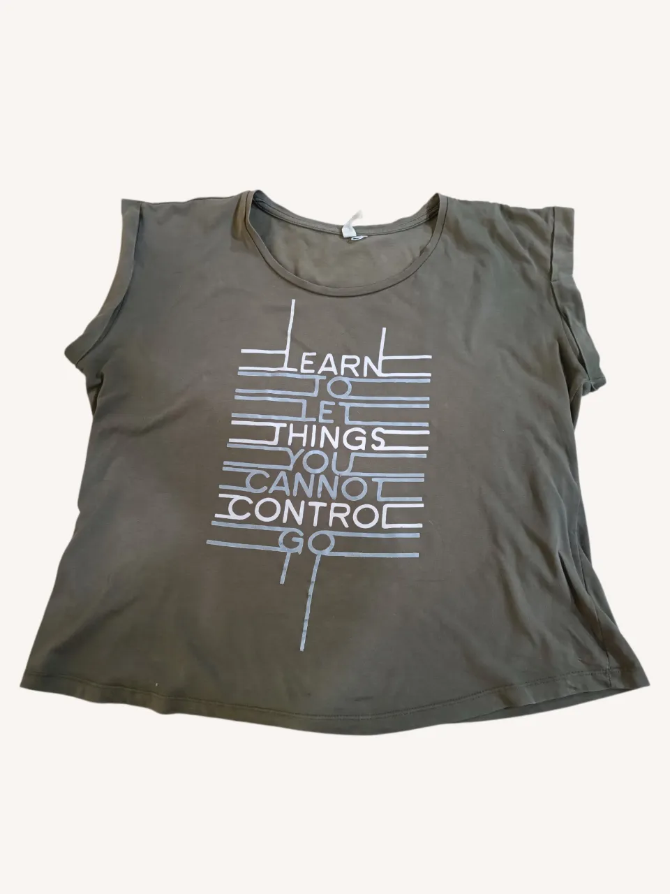 Remera muscolosa color verde militar con estampa "LEARN TO LET THINGS YOU CANNOT CONTROL GO" en blanco y gris. Ideal para un look casual y relajado.
‼️Tiene una manchita, ver última foto.