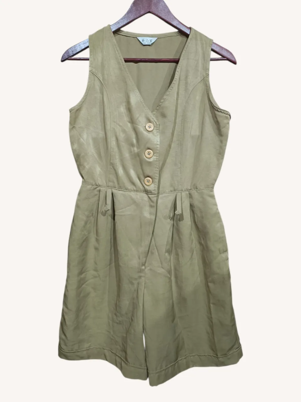 Mono corto de color verde militar, sin mangas, con cuello en V y tres botones en la parte superior. Posee bolsillos laterales y un bolsillo trasero con un botón. 
‼️Tiene pasacintos, están descosidos.