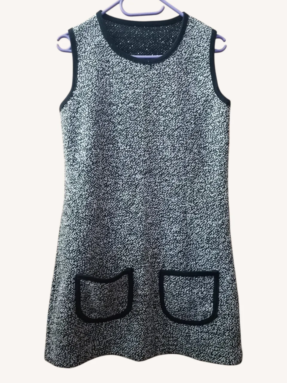 Vestido corto sin mangas, estilo 60s con cuello redondo y dos bolsillos delanteros. Diseño texturizado en blanco y negro. Tela gruesa, ideal para otoño/invierno.