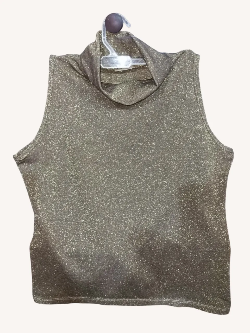 Top brilloso con cuello alto y sin mangas, ideal para un look moderno. Perfecto para salidas nocturnas o para darle un toque especial a tu outfit.