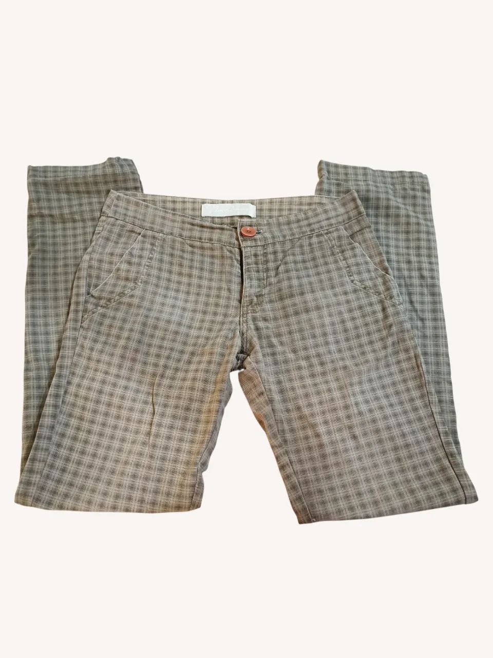 Pantalón recto a cuadros escoceses en tonos grises y beige. Posee dos bolsillos delanteros y dos traseros con tapa. 