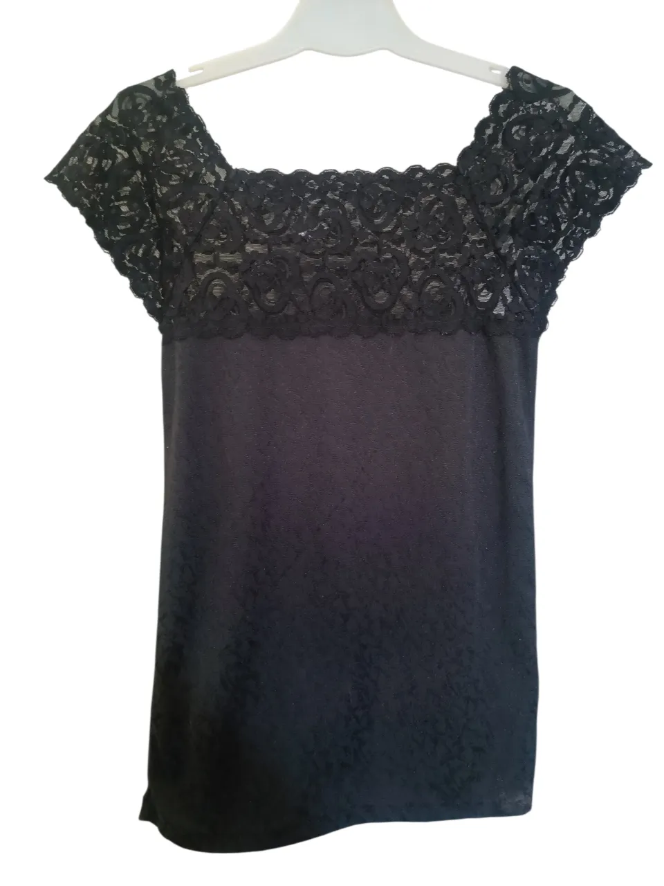 Remera negra de manga corta con detalles de encaje en el escote y mangas. Tiene un sutil estampado floral. Ideal para un look elegante y femenino.

El chaleco de la última foto también está disponible.
