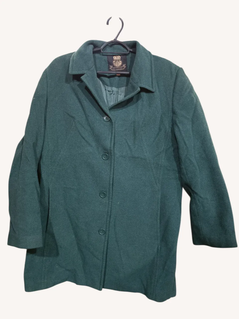 Abrigo de paño largo de color verde oscuro, con cuello solapa y botones al frente. Posee forro interior. Tiene bolsillos.
‼️ Detalles: Tiene rajado el forro en una manga, un par de descocidos y unos agujeritos. Se ve todo en las fotos.