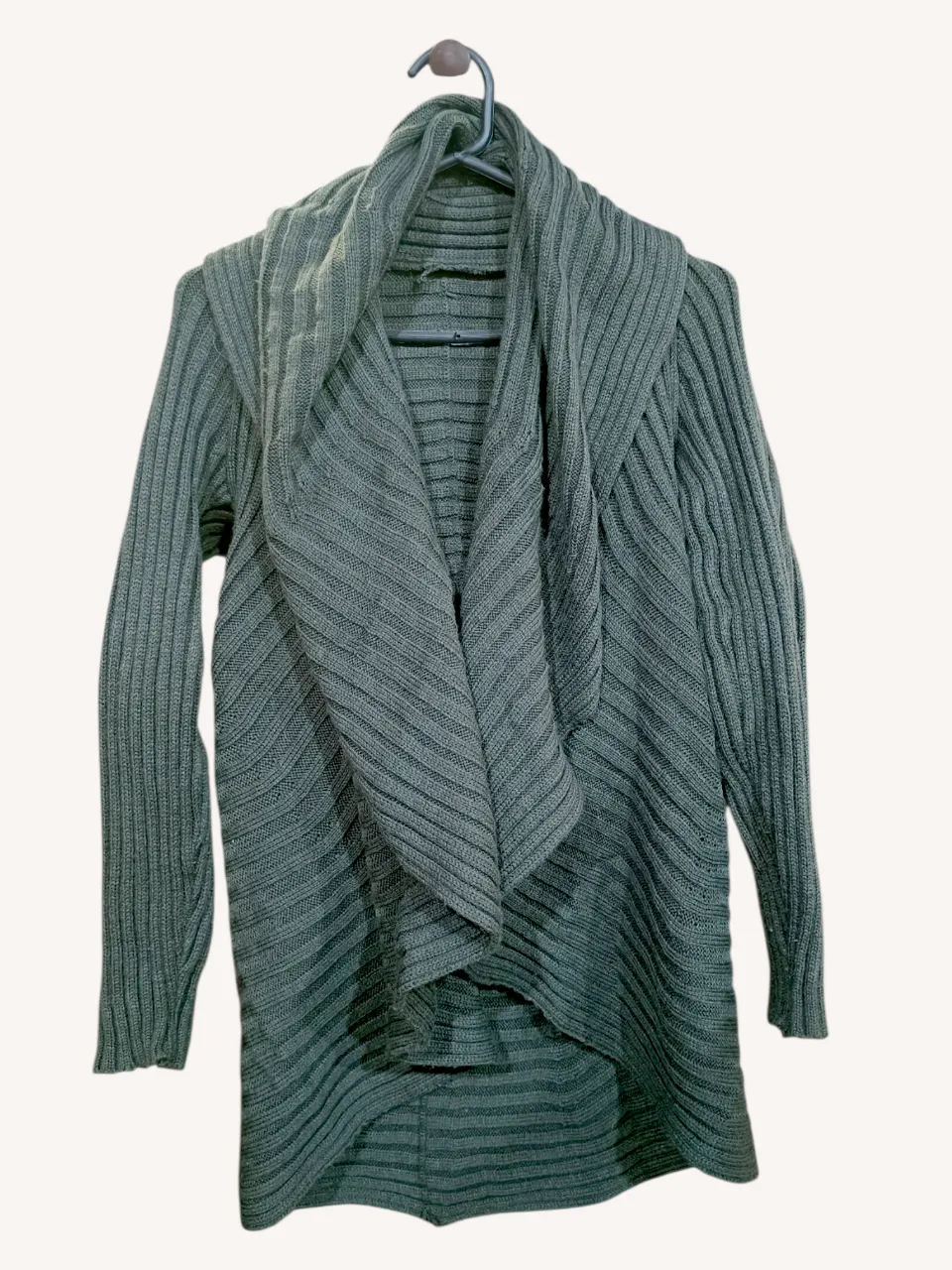Cardigan de manga larga con cuello envolvente y terminación asimétrica. Posee un diseño de líneas horizontales en relieve a lo largo de toda la prenda.