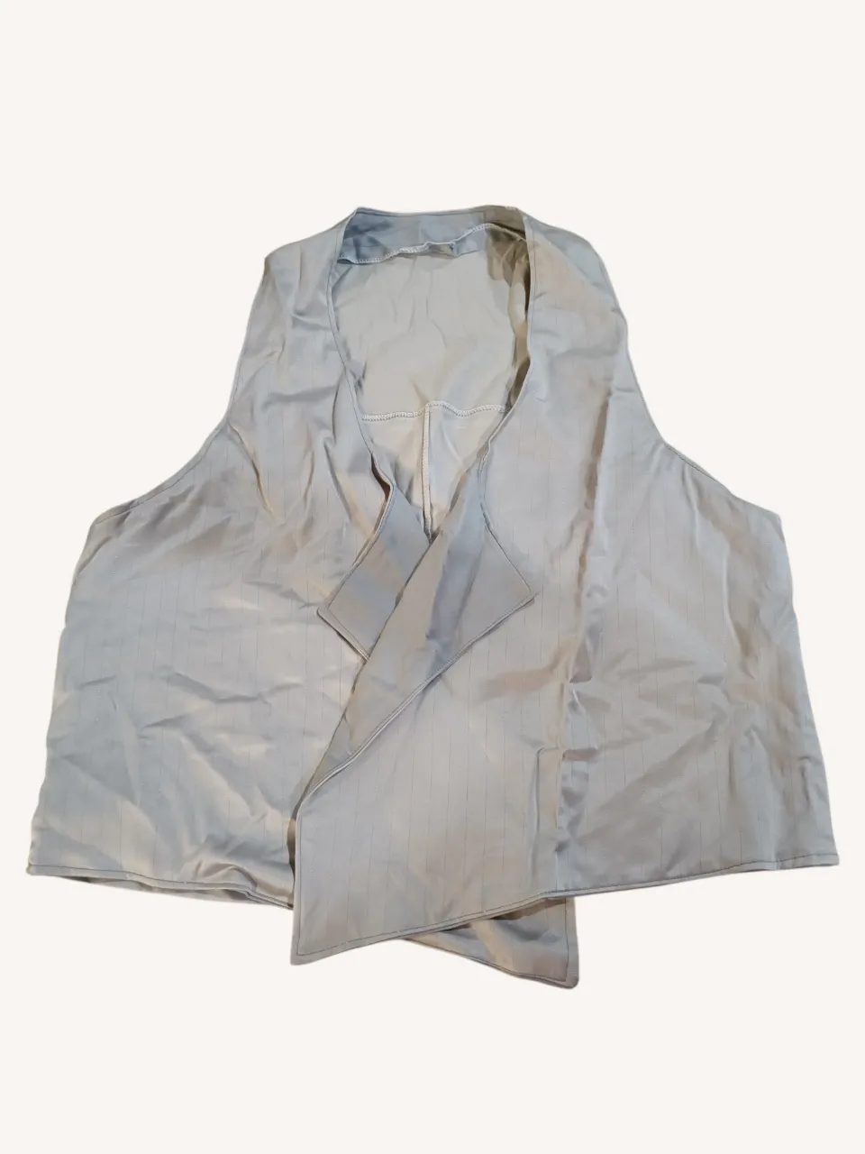 Chaleco gris con finas rayas verticales plateadas y solapa cruzada.