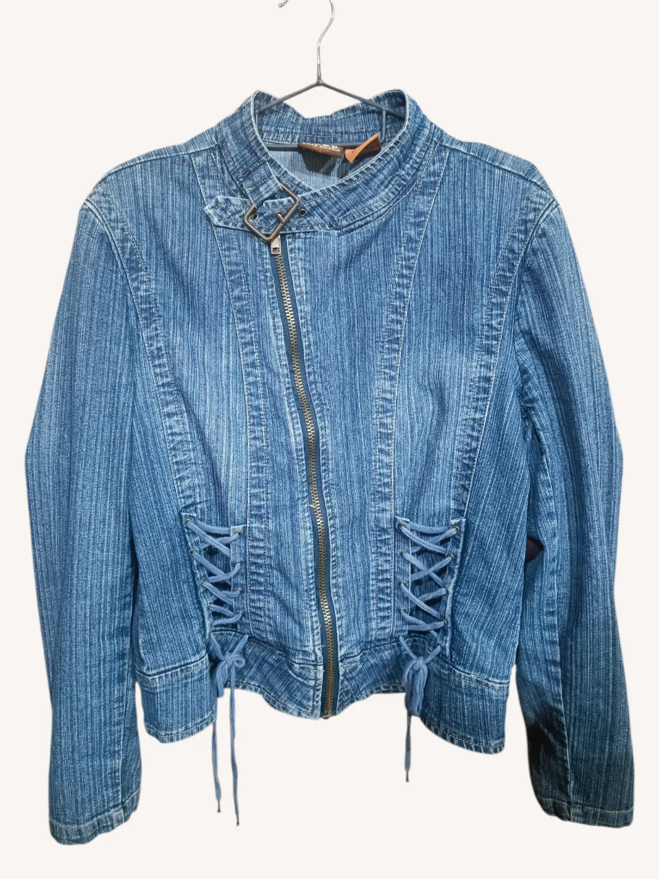 Campera de jean azul con detalles de cordones en los laterales y cierre al frente. Un clásico que no puede faltar en tu guardarropa, ideal para darle un toque canchero a cualquier outfit.