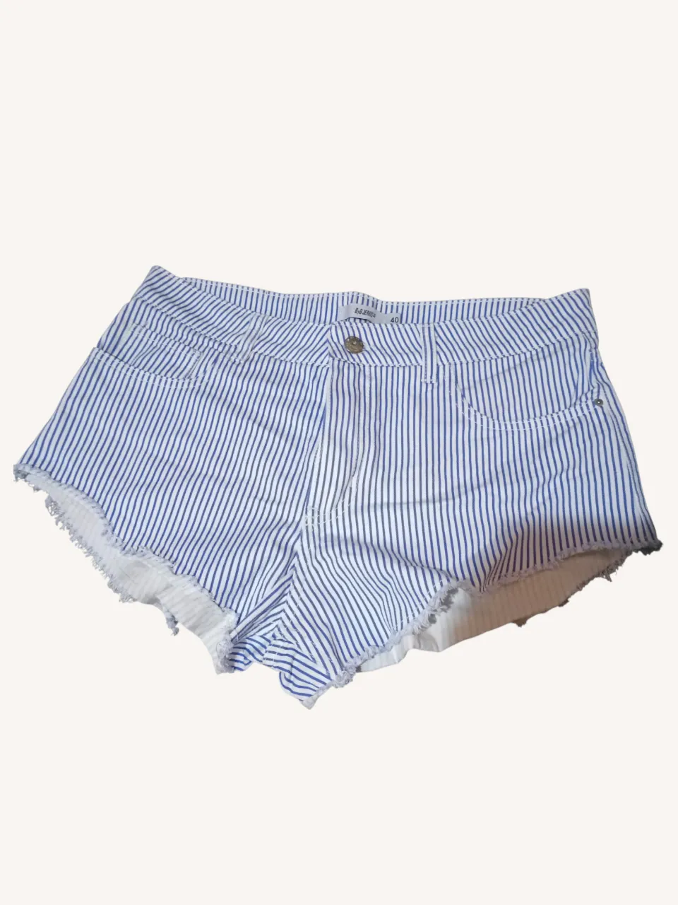 Shorts de jean a rayas blancas y azules, con detalles desflecados en los bordes.