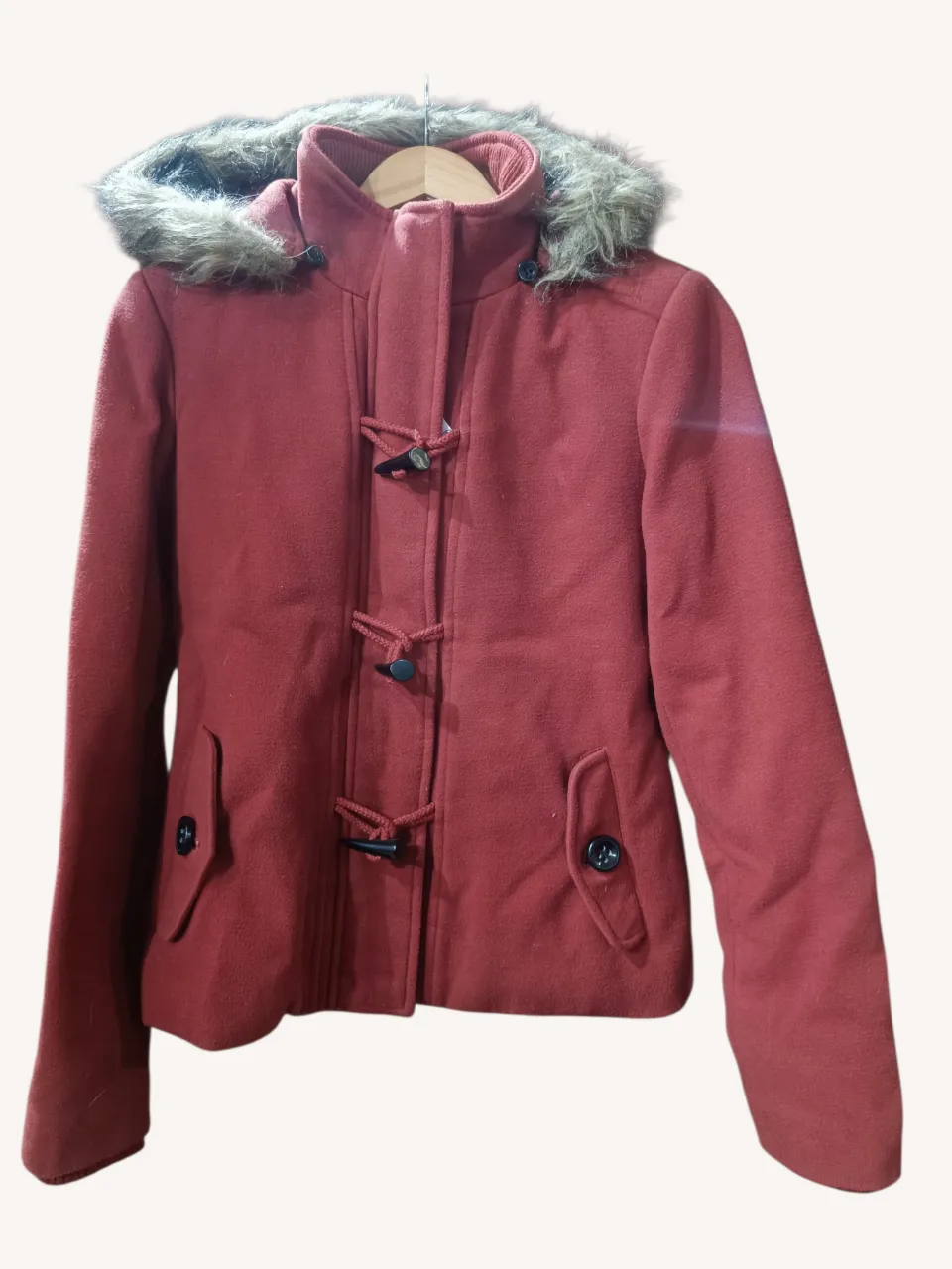 Saco de paño color ladrillo, con capucha forrada y detalle de piel sintética. Posee detalles de botones y trencillas en el frente, y puños de ribb. Ideal para el frío, con un estilo casual y moderno. Es muy calentito. Excelente estado. Capucha desmontable.