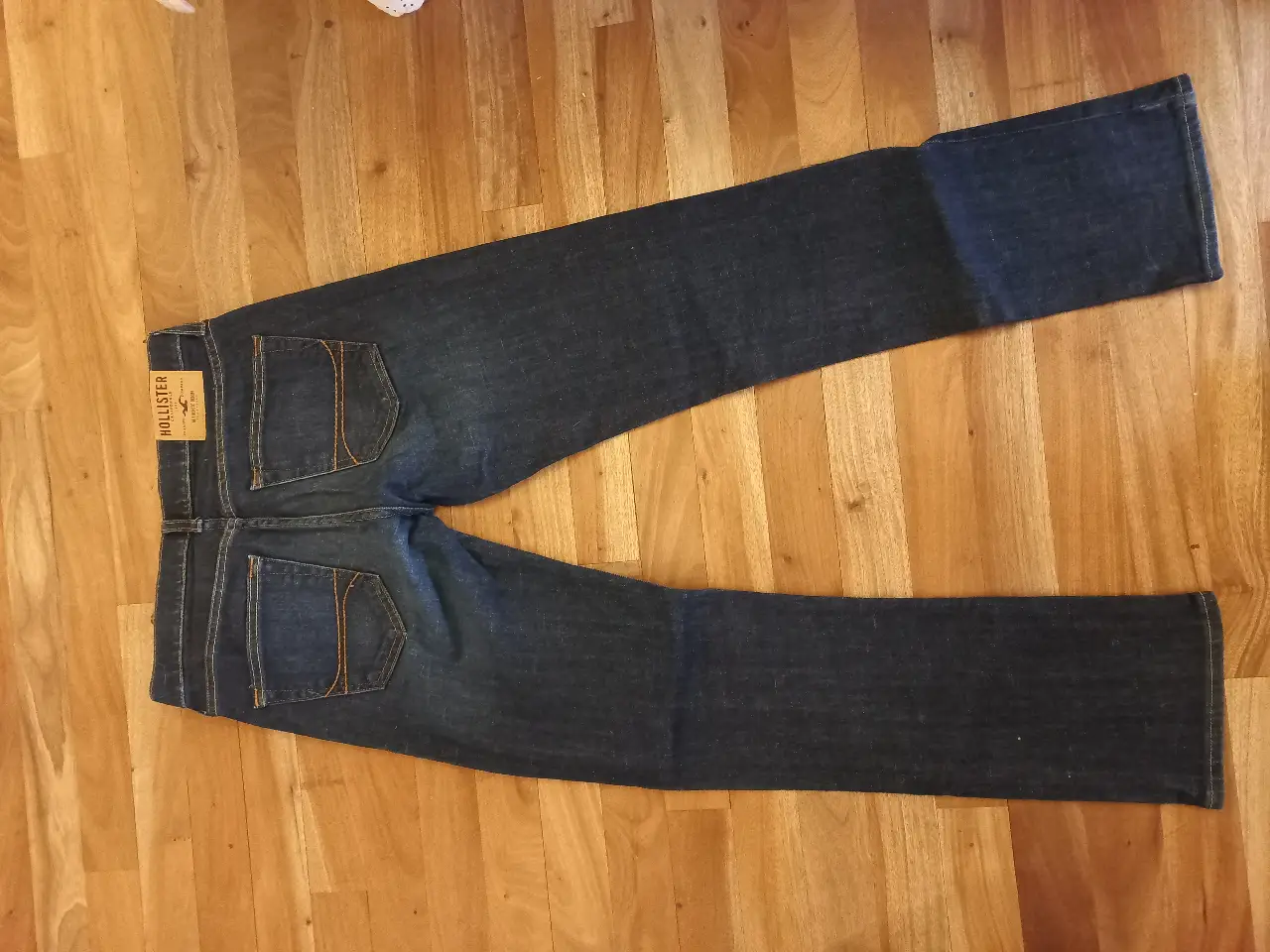 Jeans rectos de hombre, color azul oscuro, con etiqueta de la marca Hollister. Ideal para un look casual y cómodo.