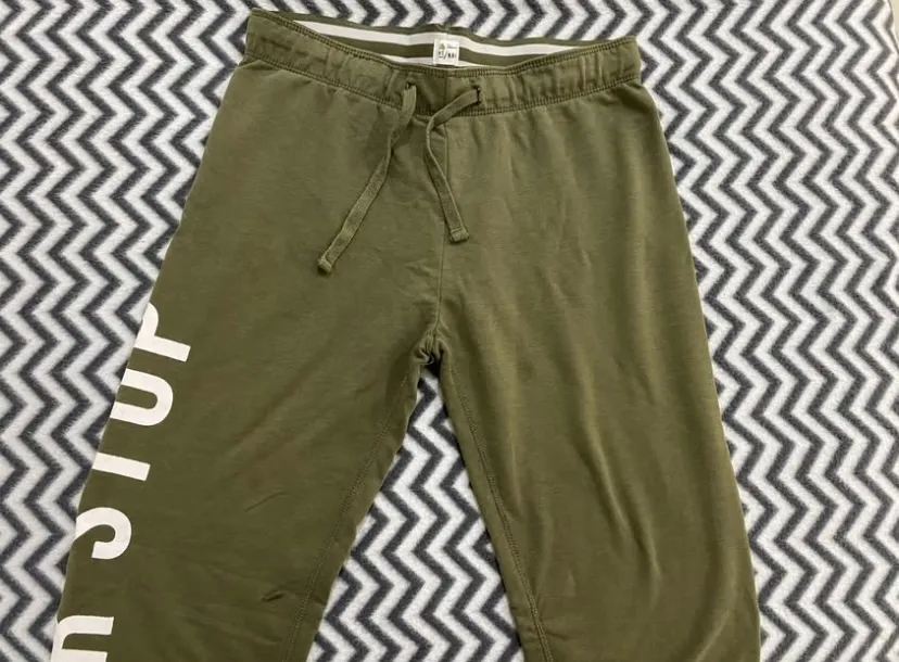 Pantalon de buzo color verde militar, con cordón ajustable en la cintura y estampa lateral blanca. Ideal para un look comfy y deportivo.
