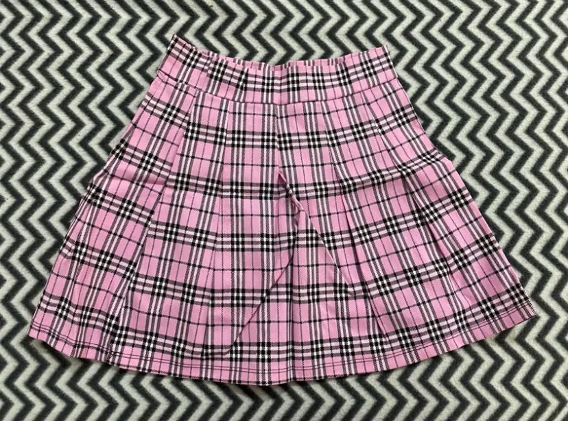 Pollera corta a cuadros rosa, negra y blanca. Tiro alto con tablas. Ideal para un look Y2K o preppy.