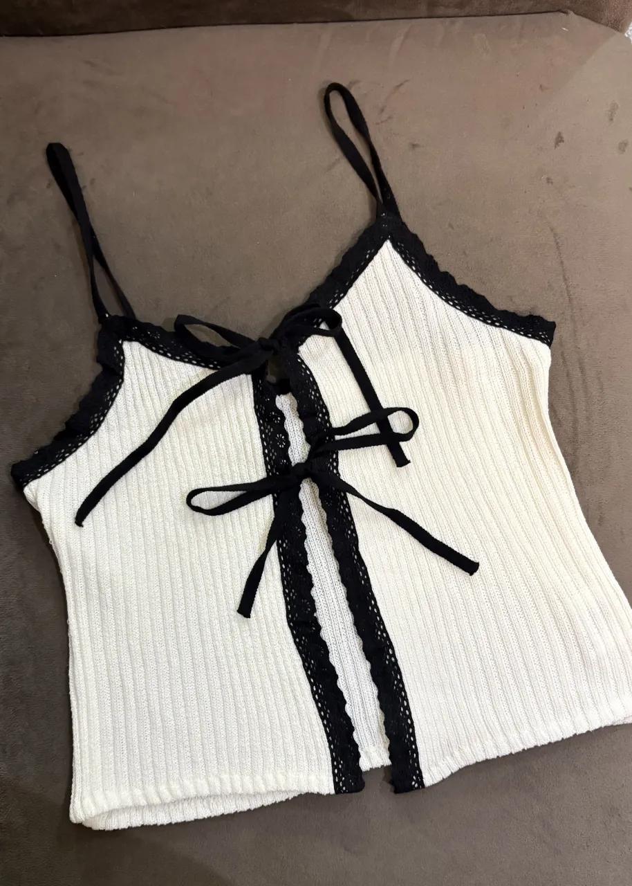 Top blanco con detalles de encaje negro y lazo al frente. Ideal para un look canchero y femenino.