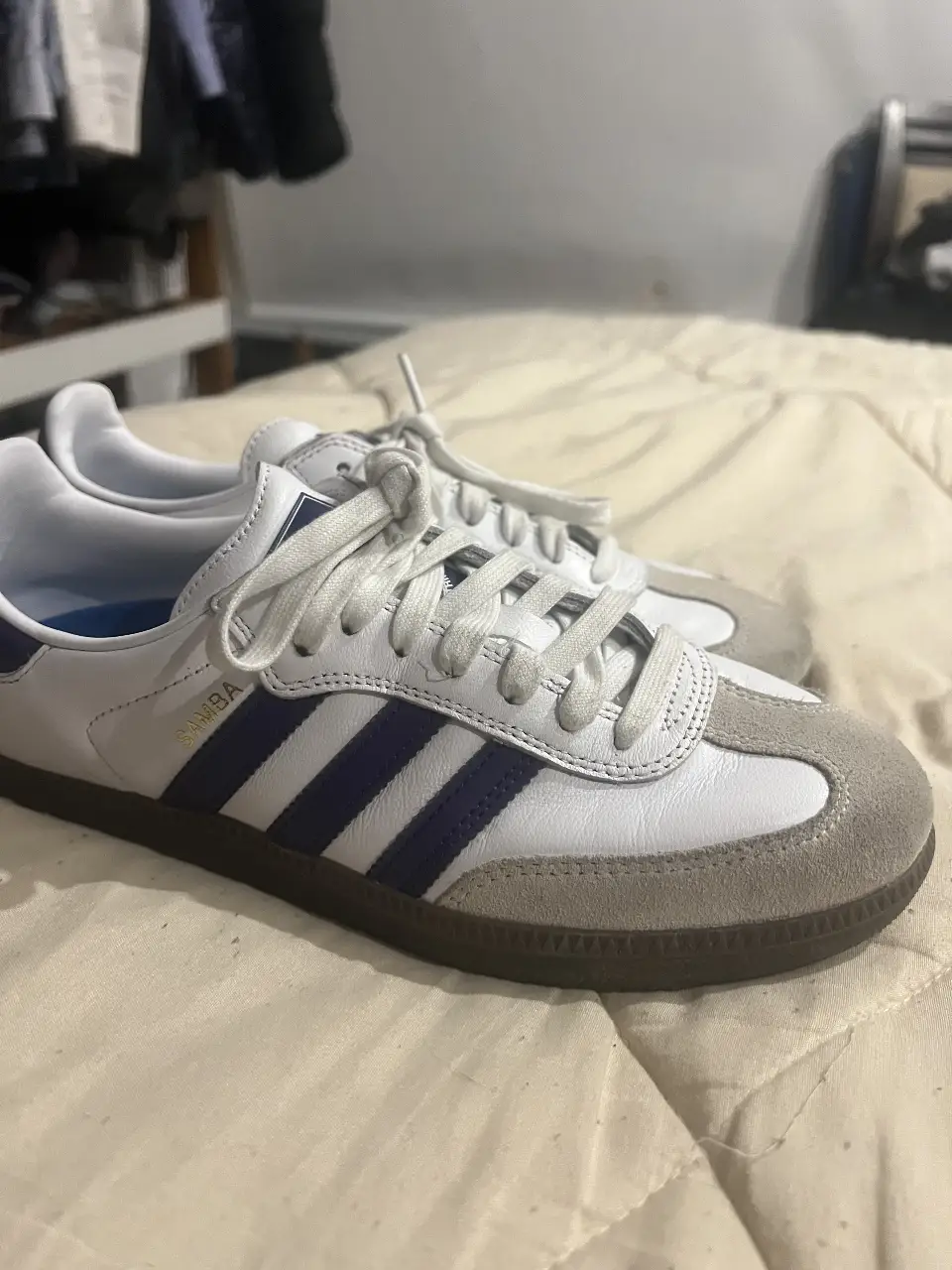 Zapatillas Adidas Samba blancas con detalles en azul. Un clásico del calzado deportivo, ideales para un look casual y cómodo.