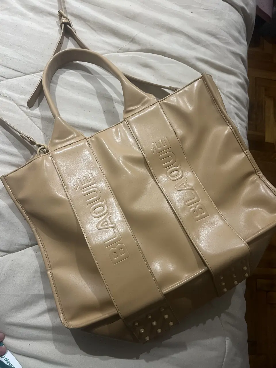 Bolso tote de cuero sintético color crudo con detalles de la marca BLAQUE en relieve. Ideal para llevar todo lo que necesitas con estilo y comodidad.