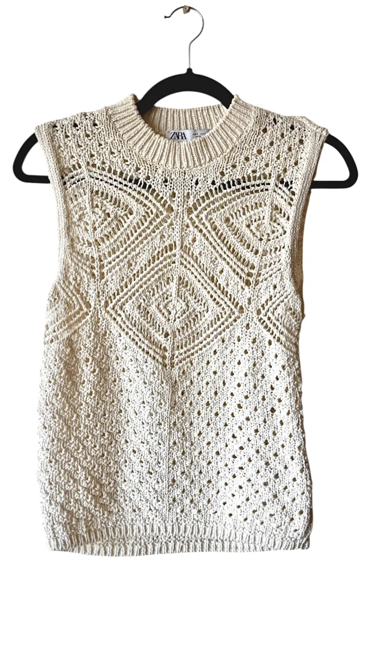 Sweater tejido sin mangas, con cuello redondo y detalles de rombos calados en el frente y la espalda. Posee terminaciones acanaladas en cuello, sisas y bajo.