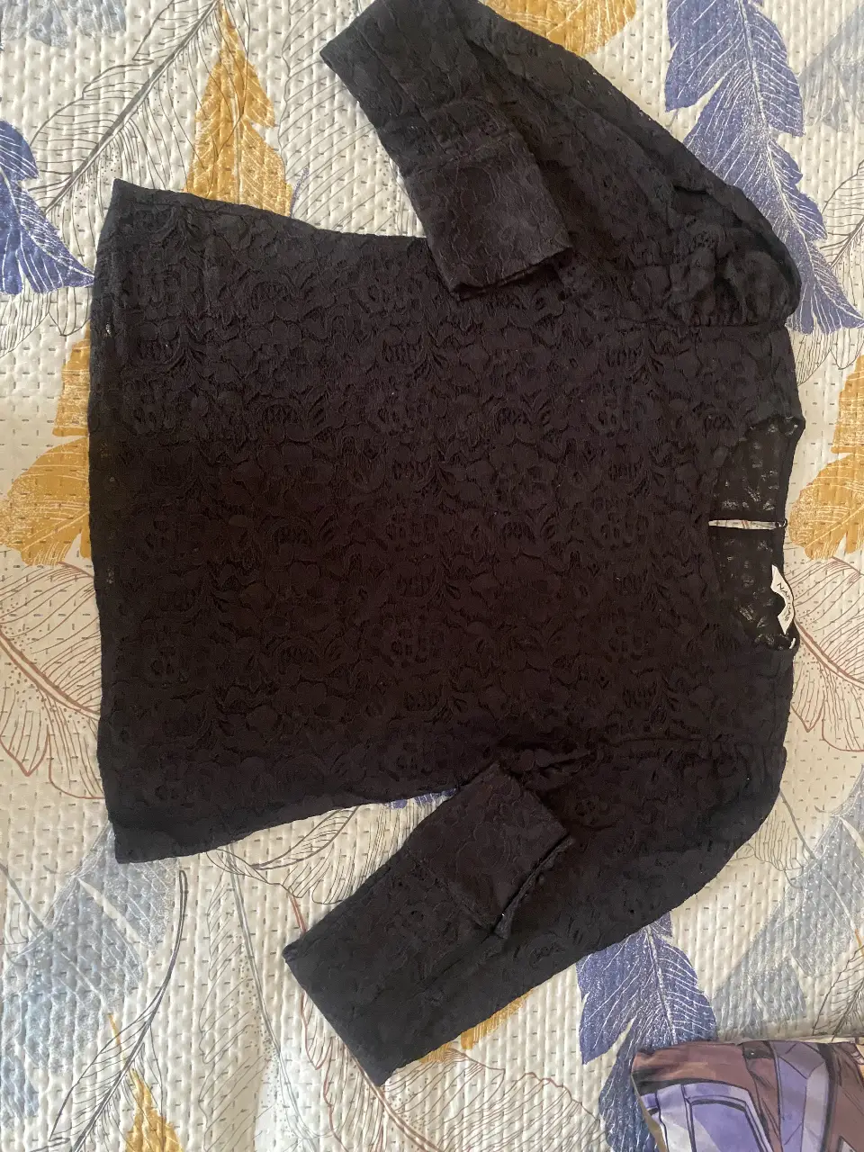 Blusa de encaje negro, manga larga con detalles de botones en los puños. Ideal para un look elegante y sofisticado.