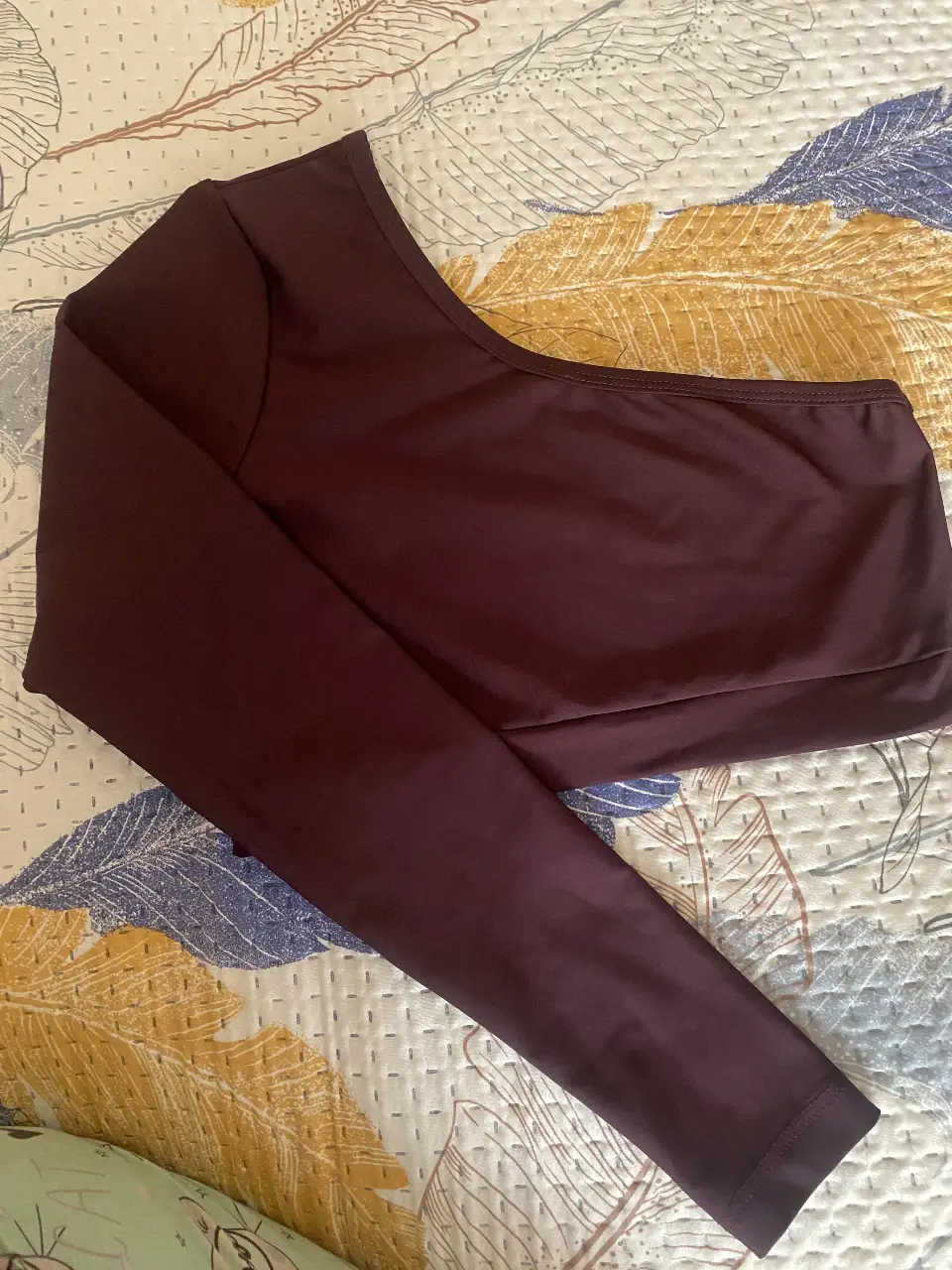 Top manga larga asimétrico en color borgoña, ideal para un look moderno y sofisticado. Perfecto para combinar con jeans, faldas o deportivo 