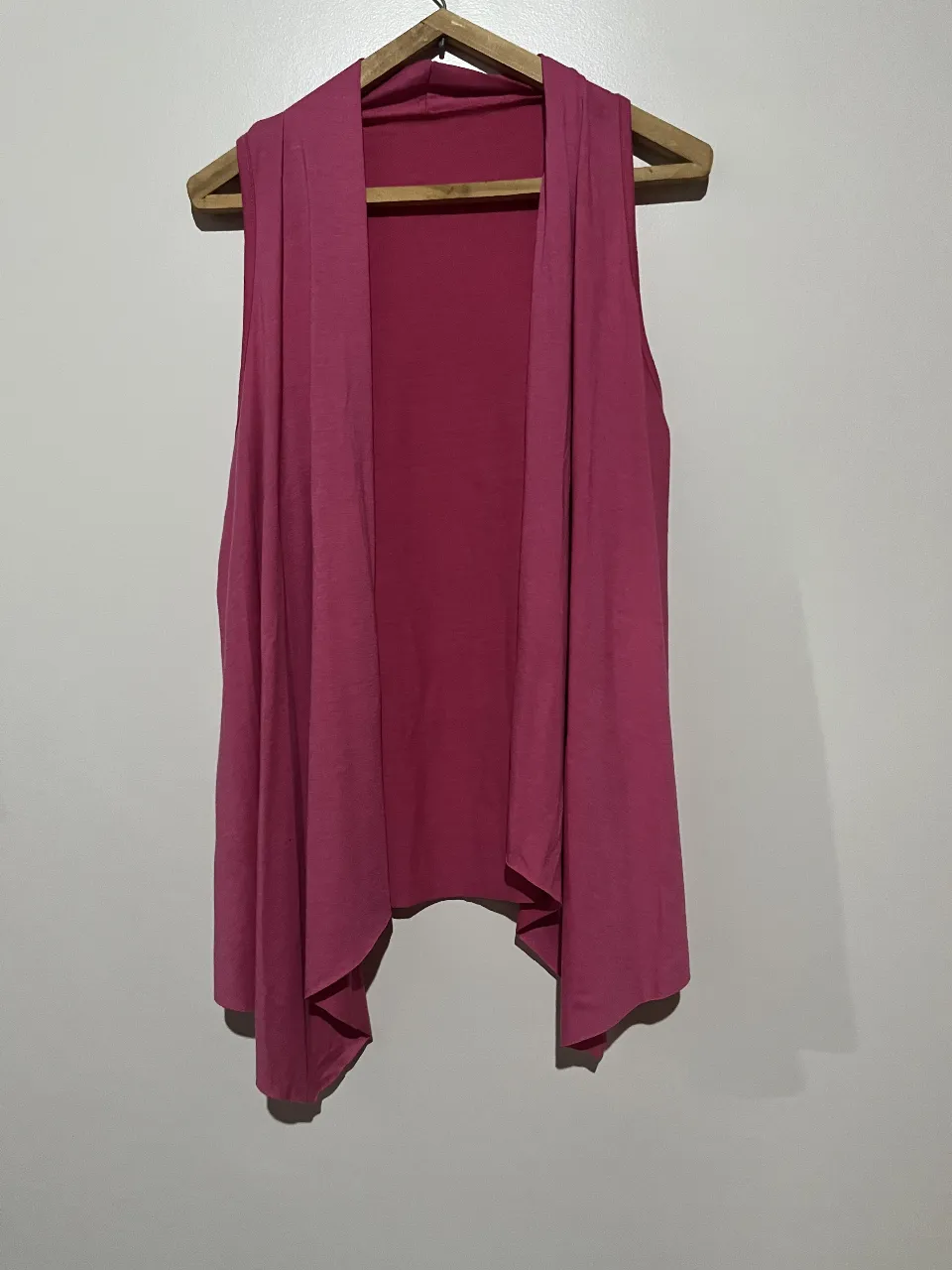 Chaleco sin mangas de color rosa, con diseño suelto y corte asimétrico. Ideal para un look casual y moderno.