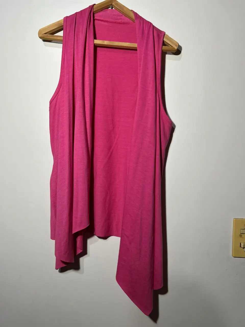 Chaleco sin mangas de color rosa, con diseño suelto y corte asimétrico. Ideal para un look casual y moderno.