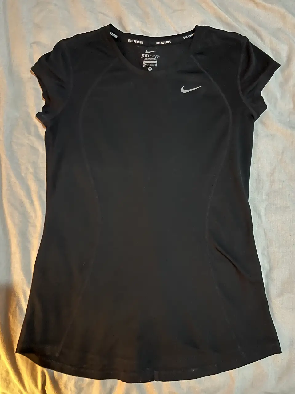 Remera deportiva Nike Dri-Fit negra para mujer, talle XS. Ideal para running y entrenamientos. Con logo de la marca en plateado.