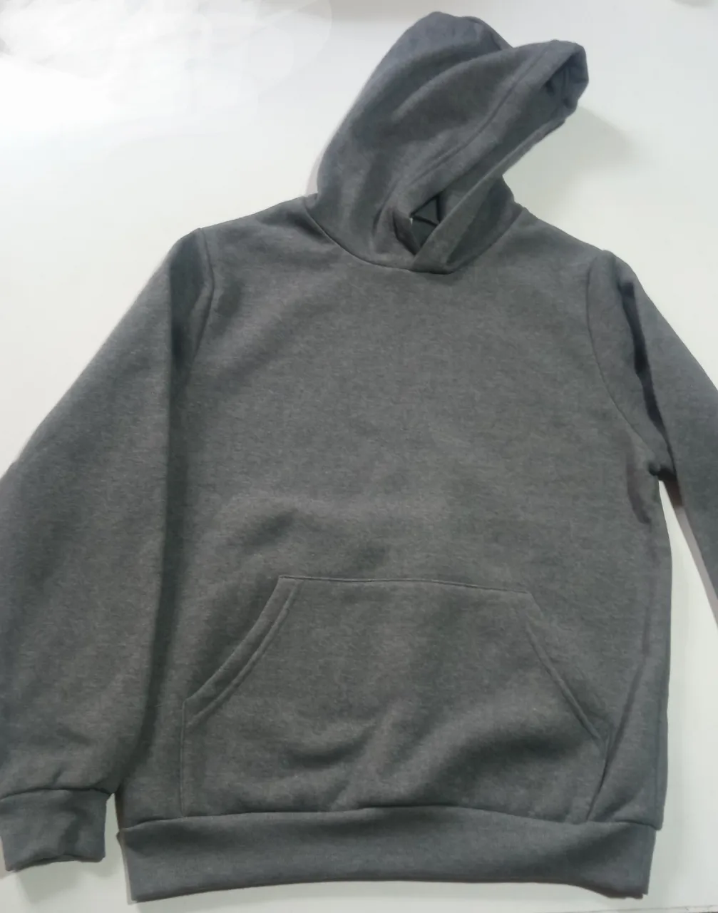Buzo canguro de friza unisex, color gris, con capucha y bolsillo frontal. Ideal para un look casual y cómodo.