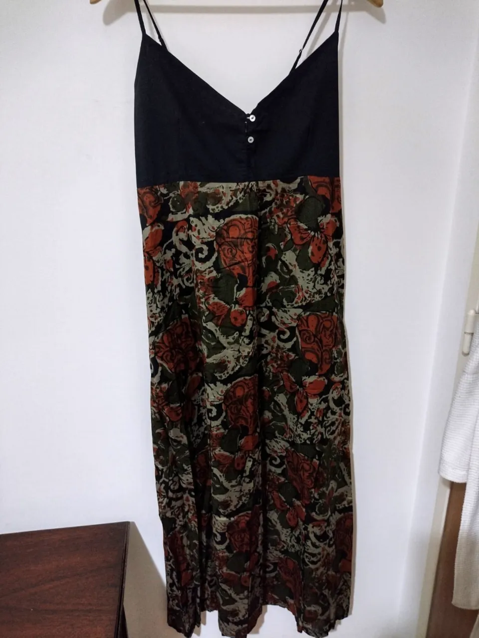 Vestido largo estampado con breteles finos y detalles de botones en el busto. La parte superior es lisa y la falda tiene un estampado floral vibrante en tonos verdes y naranjas. Ideal para un look fresco y bohemio. Espalda elastizada y breteles regulables.  usado solo 1 vez. talle M sería  un 44