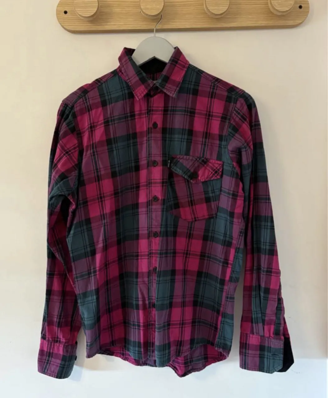 Camisa a cuadros de manga larga con botones al frente y un bolsillo en el pecho.