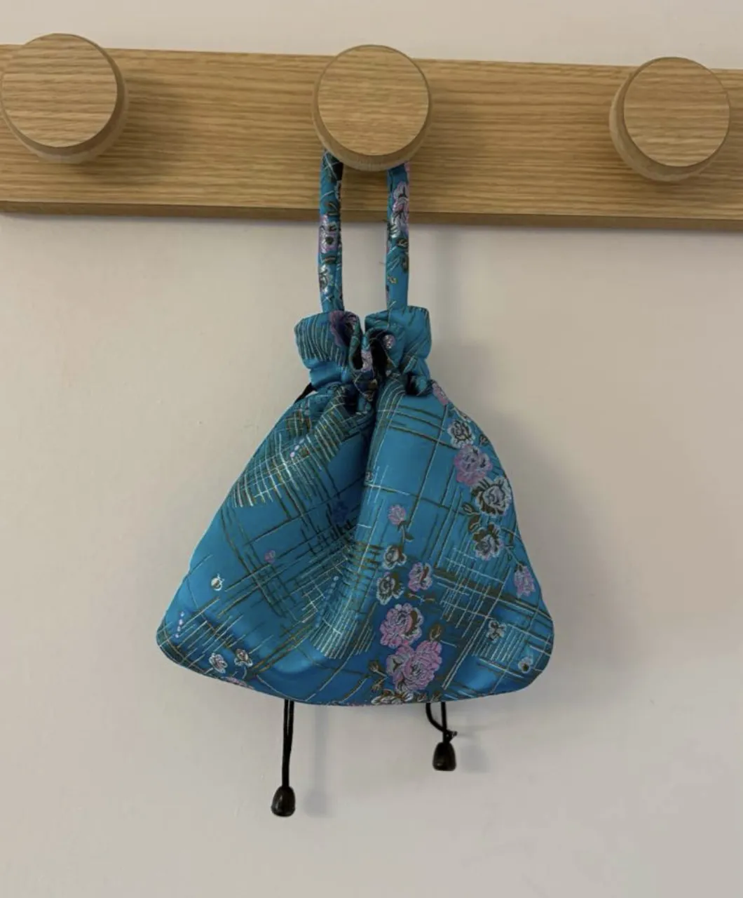 mini bolsito color turquesa con estampado floral y detalles metalizados. de tela suave y con cierre fruncido con cordón
medida 17x19cm