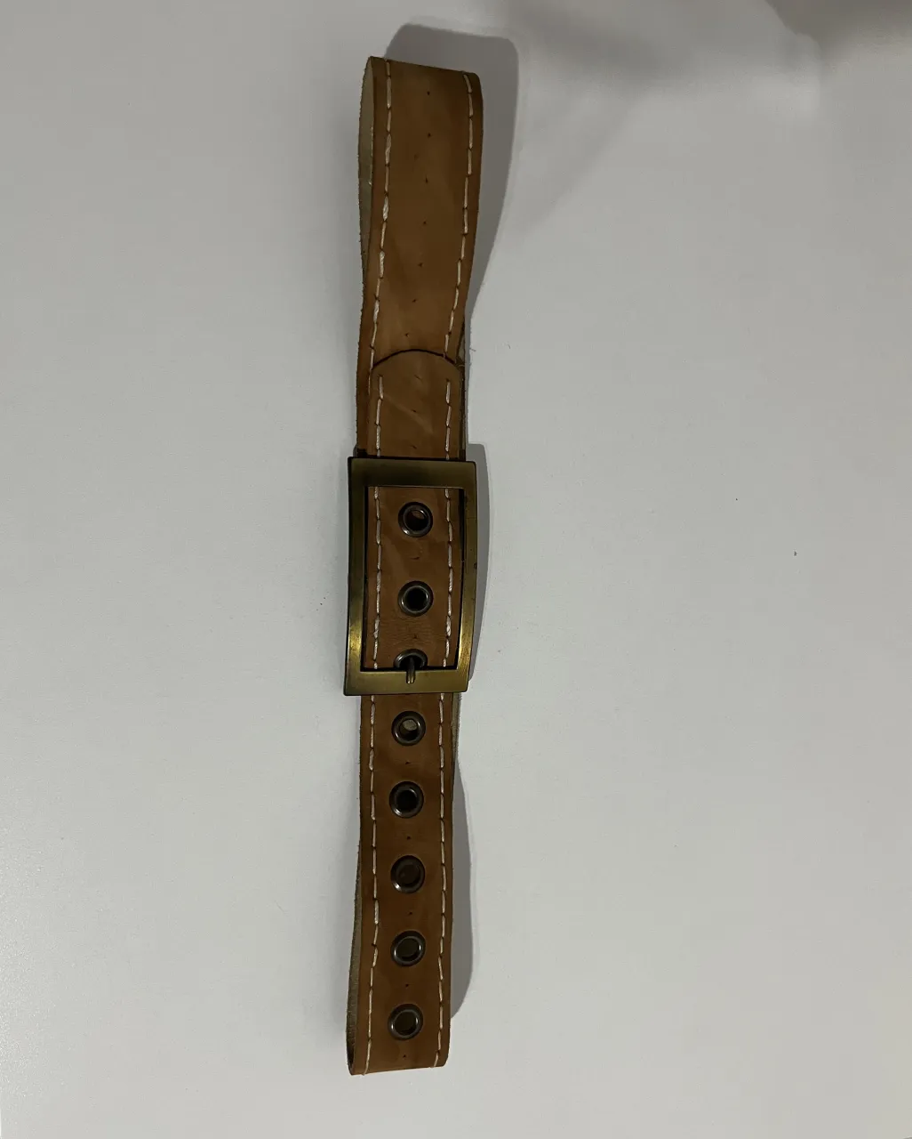 Cinturón de cuero marrón gamuzado estilo 2000’ con hebilla metálica dorada y detalles de costura blanca. Posee múltiples ojales para ajuste.
Medida: 95cm de largo 