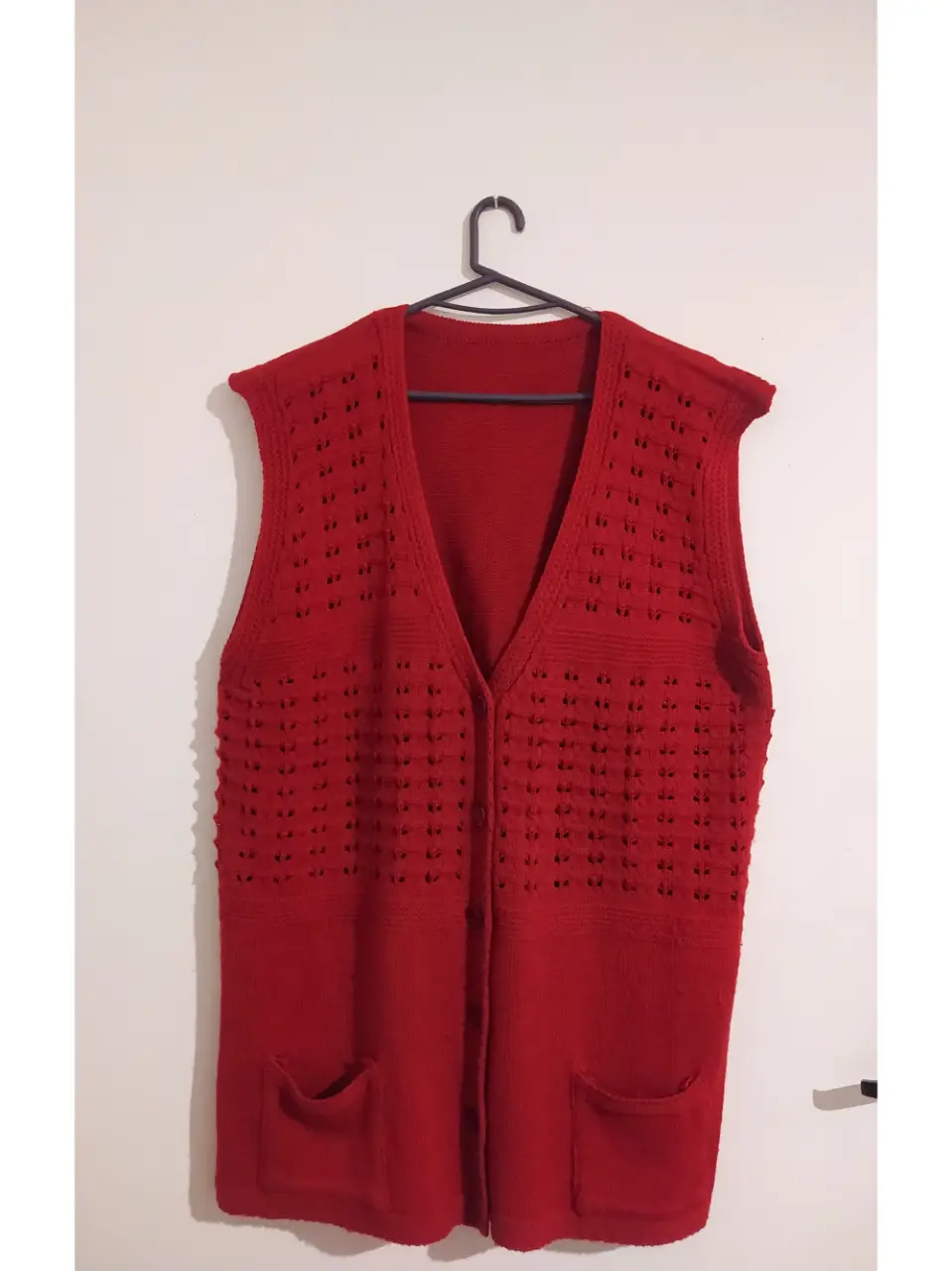 Chaleco tejido de punto, color rojo, con dos bolsillos delanteros y botones. Ideal para un look casual y abrigado.