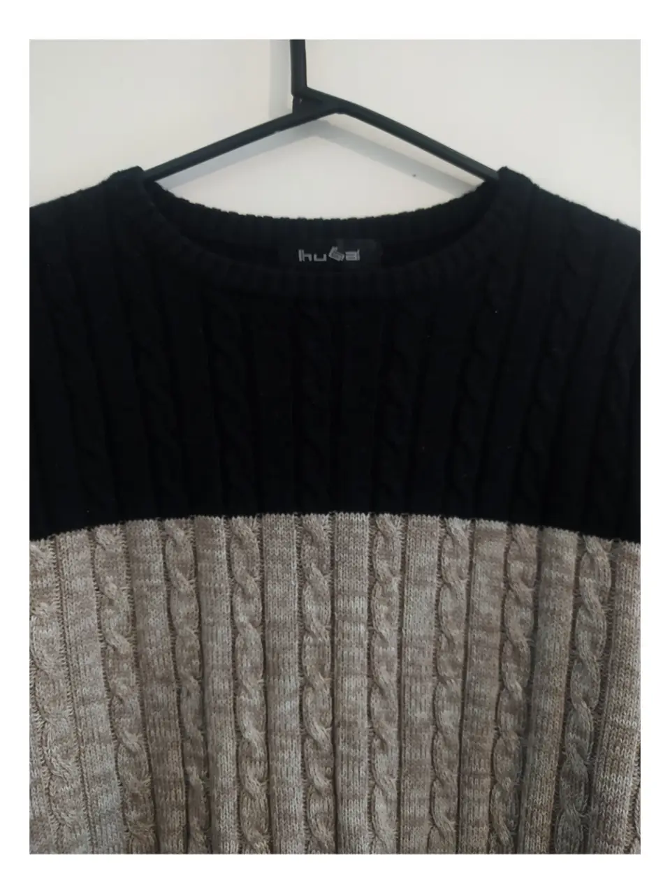 Sweater de hombre con diseño bicolor. La parte superior es de color negro, mientras que la inferior es crema con un diseño de trenzas. Ideal para un look casual y abrigado.
