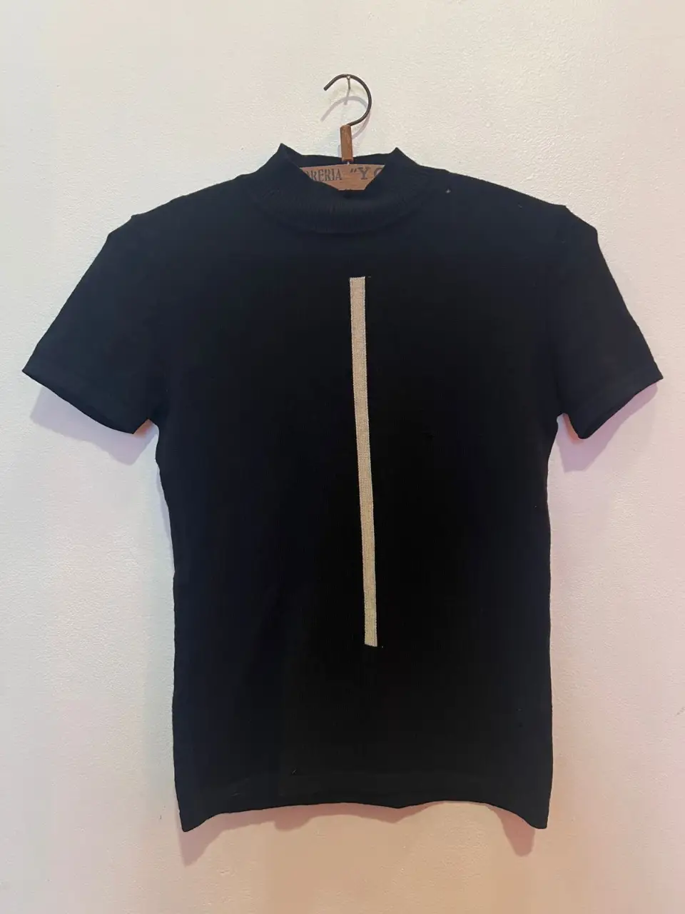 Remera negra de manga corta con cuello alto y detalle de línea vertical en color crema. Ideal para un look moderno y versátil. TALLE : SMALL //largo :57cmm/ ancho:34cm