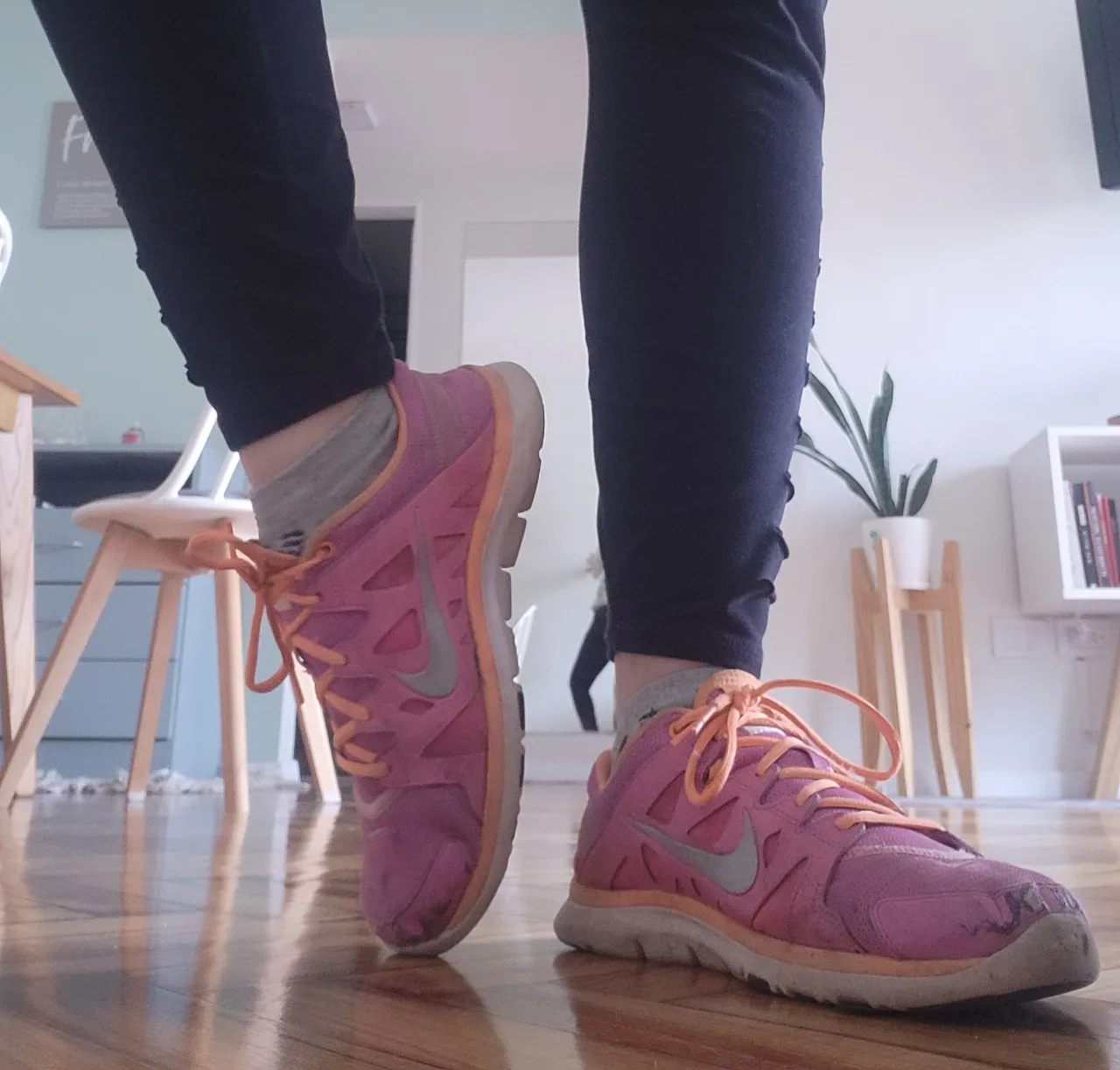 Zapatillas deportivas Nike Free Run de mujer, color rosa con detalles en naranja y el logo de la marca en gris. 