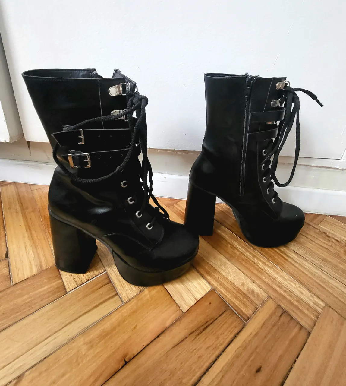 Botas negras de caña alta con plataforma y taco ancho. Cierre lateral y detalles de hebillas y cordones.