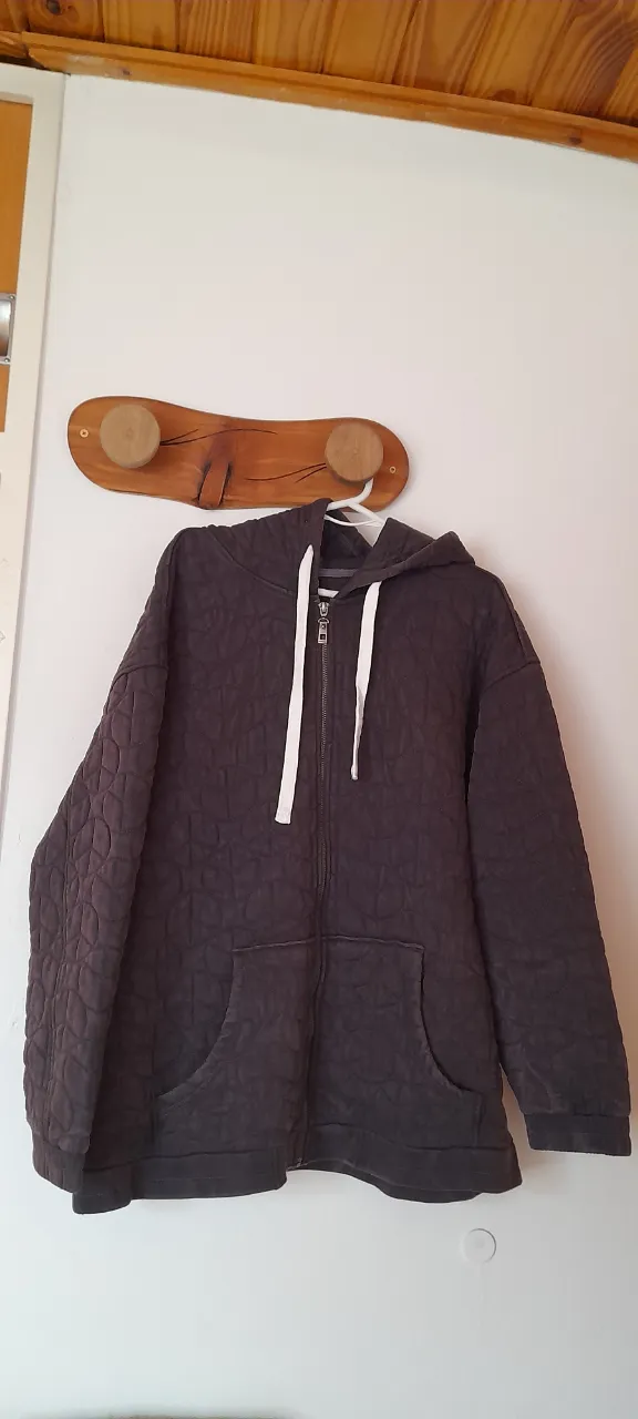 Buzo con capucha, cierre al frente y bolsillos tipo canguro. Posee un diseño acolchado con rombos.