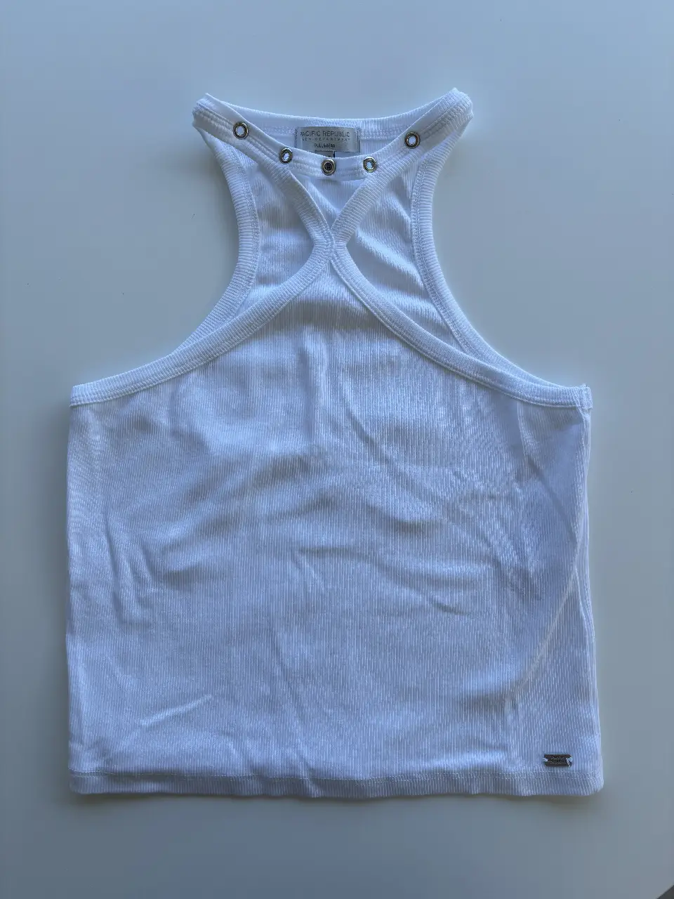 Top blanco de mujer, estilo musculosa con cuello halter y detalles de ojales. Ideal para un look casual y fresco.