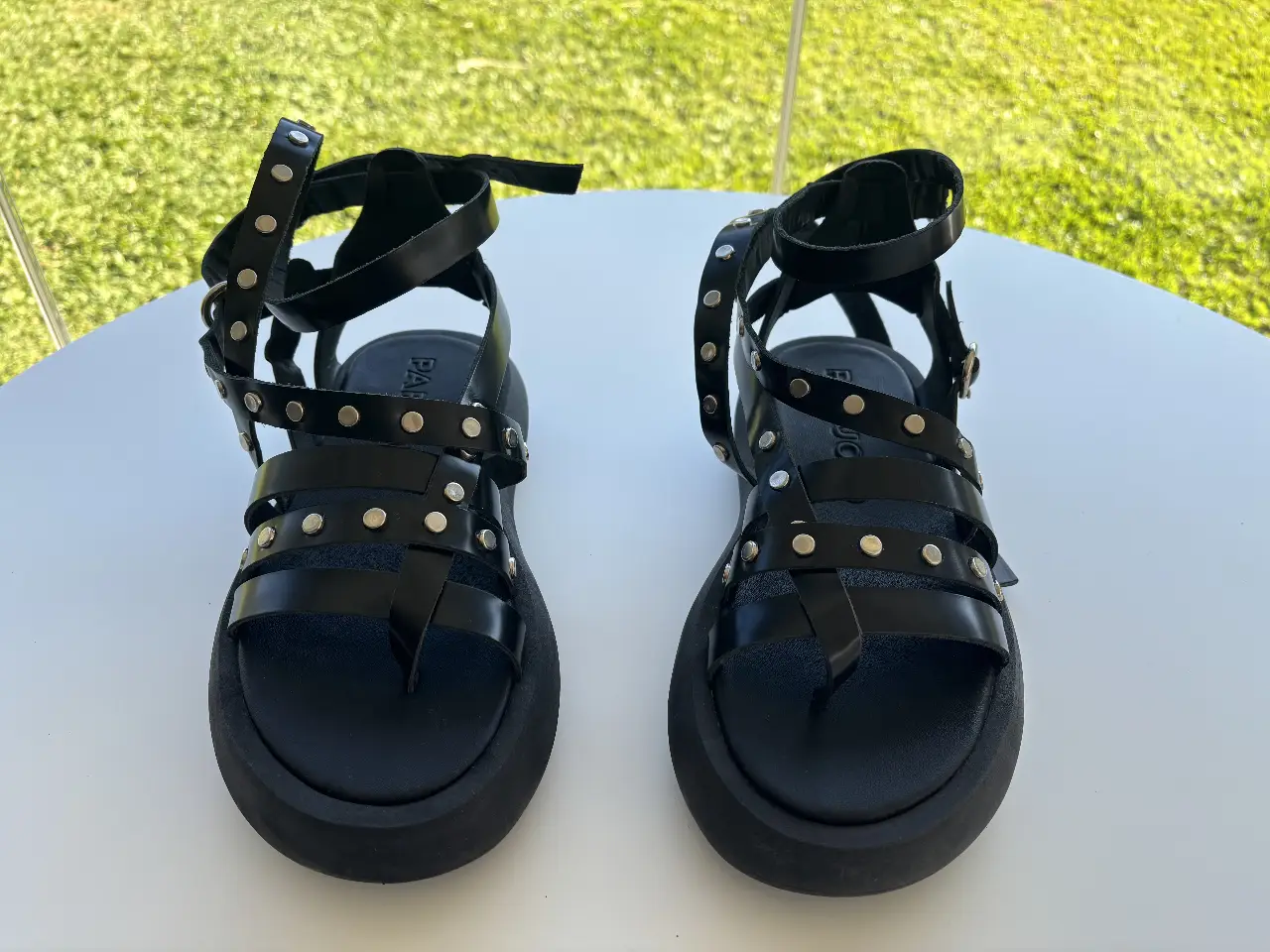 Sandalias negras con detalles de tachas plateadas. Diseño con tiras y plataforma y se ata en el tobillo. Ideales para un look moderno, audaz y canchero.