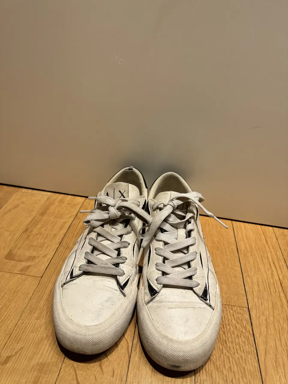 Zapatillas blancas de cuero sintético con detalles en negro. Diseño casual con cordones blancosny suela de goma. Ideales para un look urbano y cómodo.