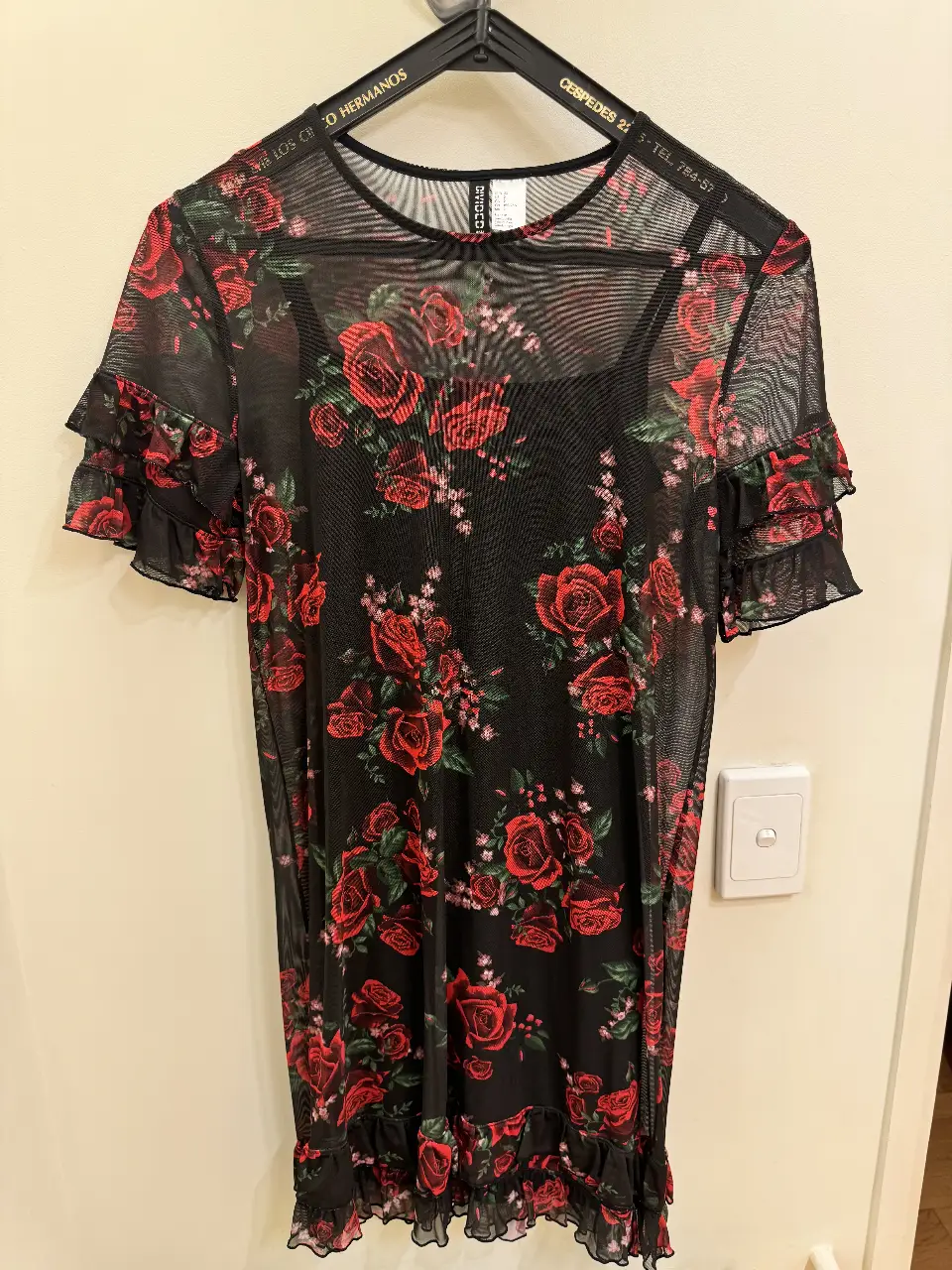 Vestido mini de red con estampado de rosas rojas. Tiene mangas cortas con volados y un cuello redondo. Ideal para un look de fiesta o salida.