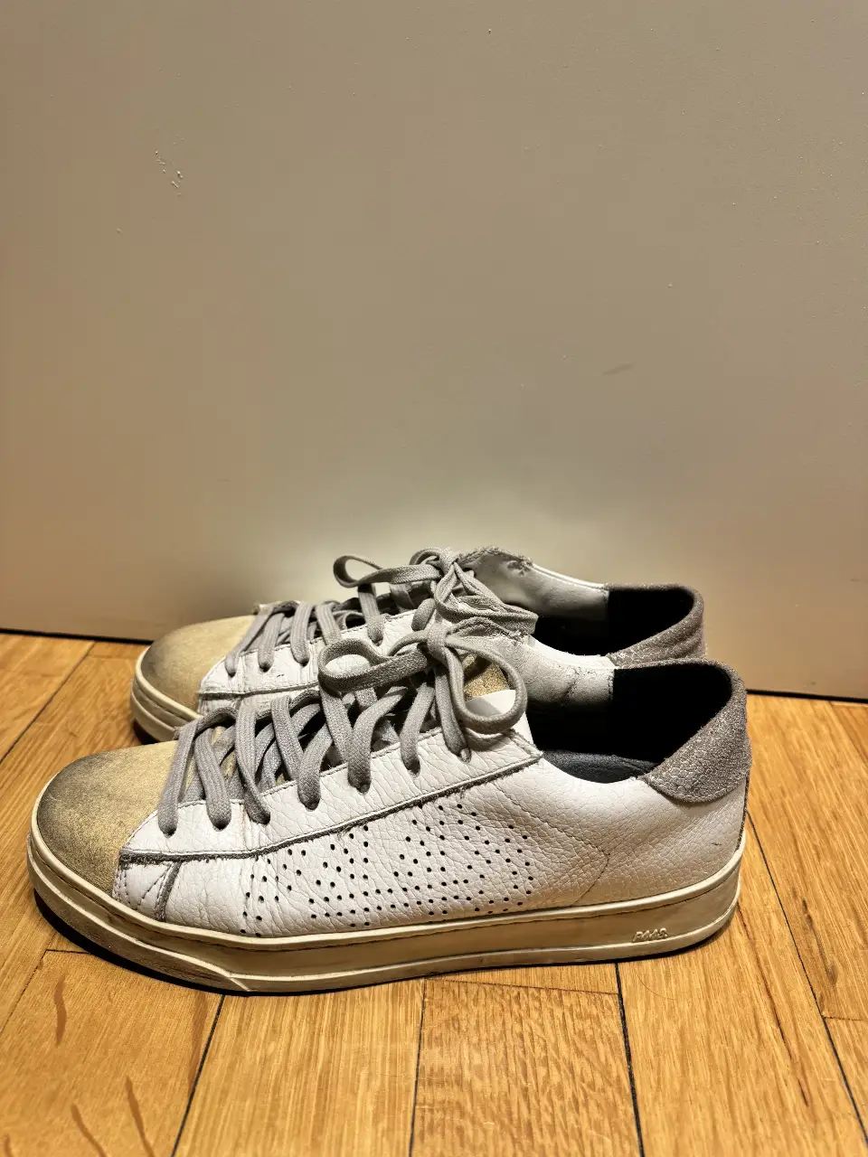 Zapatillas de cuero blancas con detalles en gris y beige. Ideales para un look casual y cómodo.