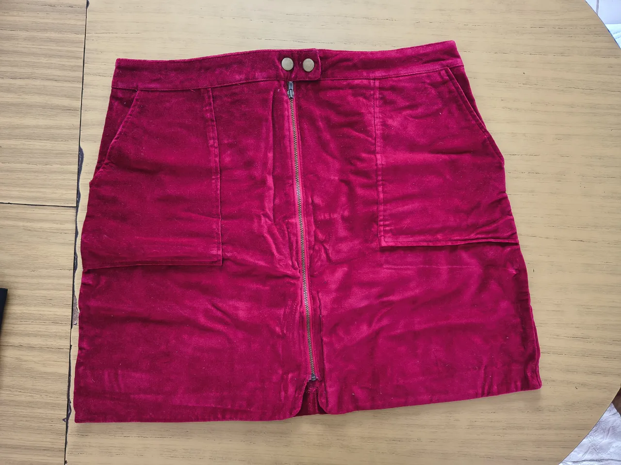 Pollera corta de pana/plusg color bordo, con cierre al frente y bolsillos. Ideal para un look canchero y moderno.