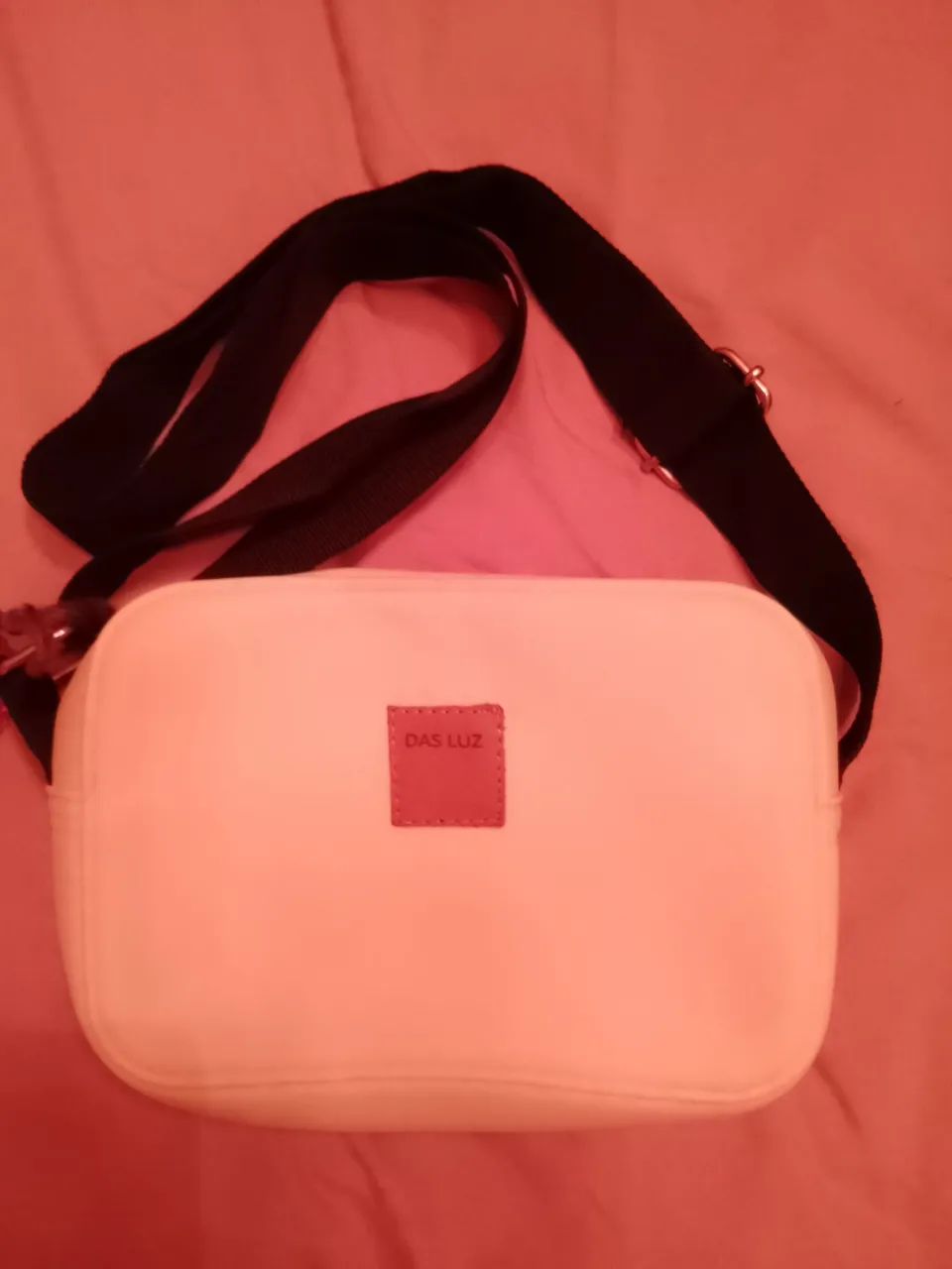 Bandolera amarilla fluorescente de material sintético,goma impermeable, con correa negra ajustable. Tiene  un parche de cuero que dice "DAS LUZ". Ideal para el día a día o salidas casuales.