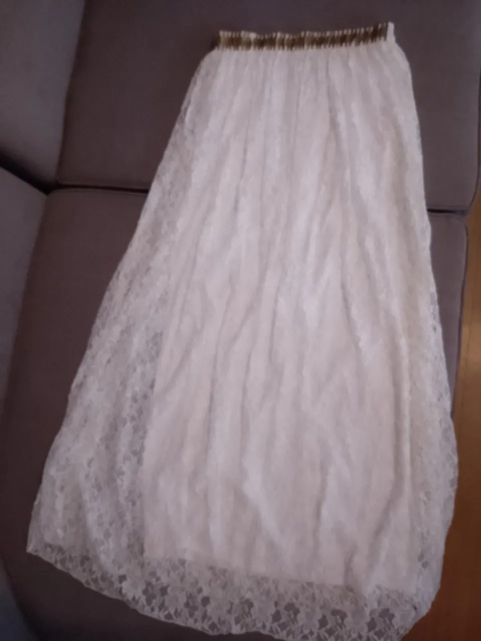 Pollera larga blanca de encaje con detalles dorados en la cintura. Ideal para un look romántico y delicado.