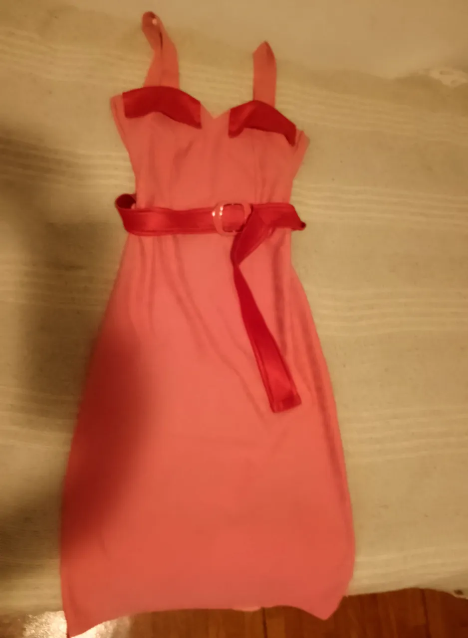 Vestido rosa con cinturón rojo y detalles en los hombros. El cinturón es de satén con hebilla plateada.