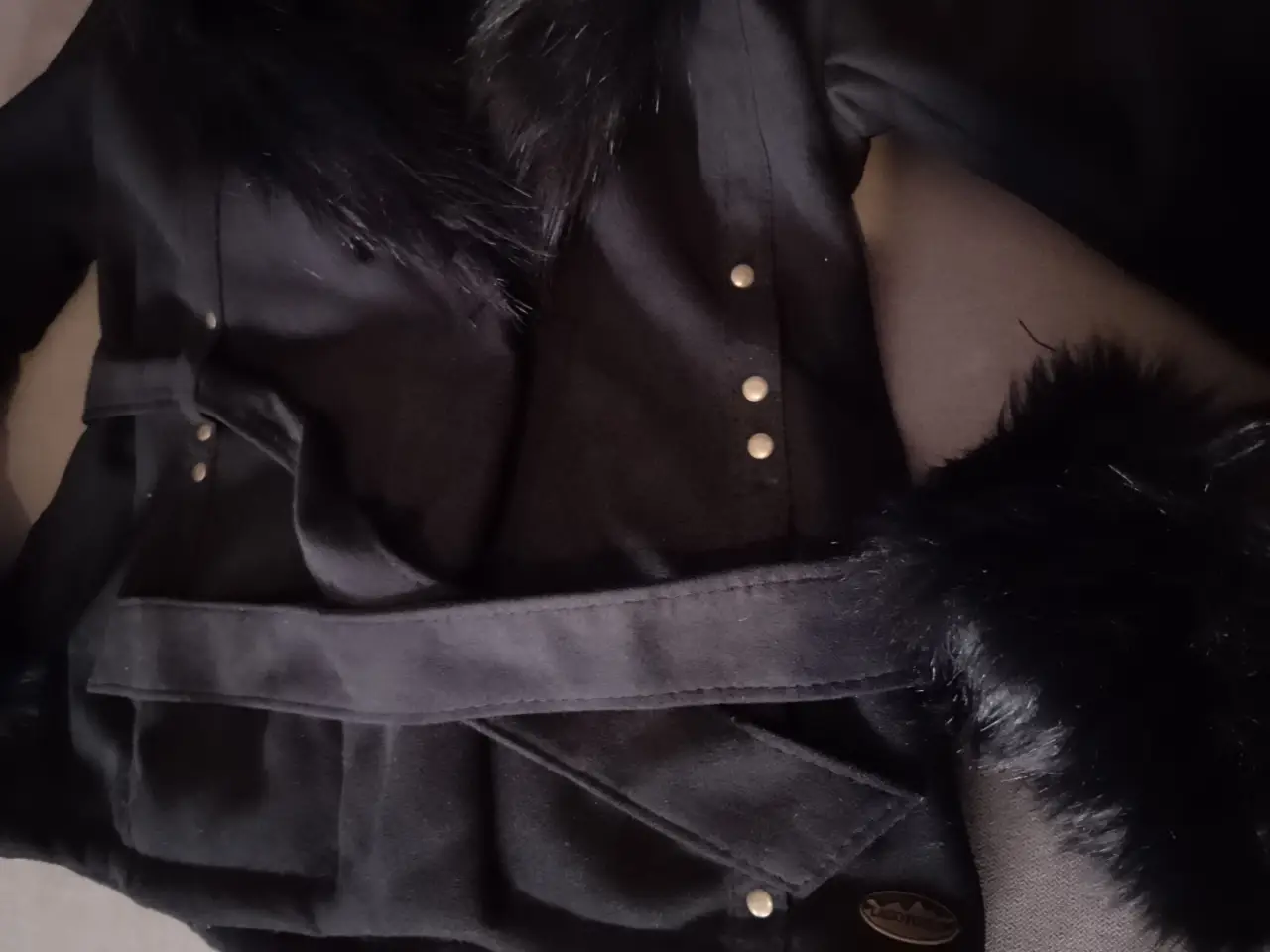 Tapado negro con detalles de piel en cuello y puños, con cinturón para ajustar la cintura. Marca Lago Puelo Estilo elegante y abrigado, ideal para el invierno.