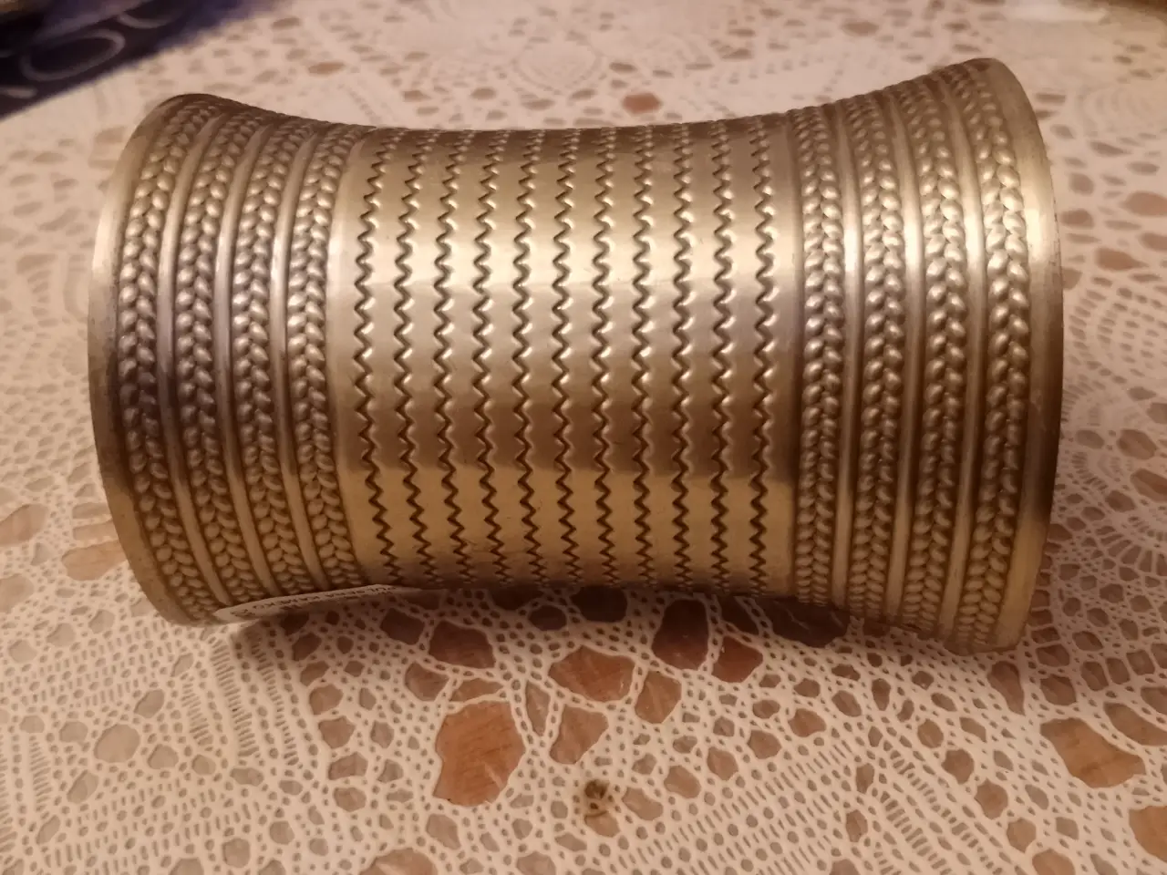 Pulsera ancha de metal dorado con diseño labrado y detalles en relieve. Ideal para complementar cualquier look con un toque bohemio y artesanal.