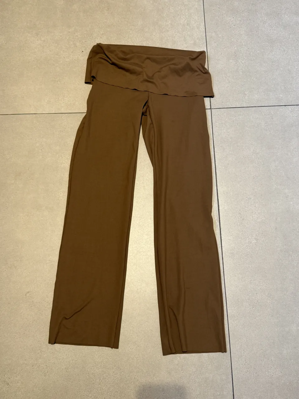 Pantalón marrón de tela con cintura ancha y fruncida.