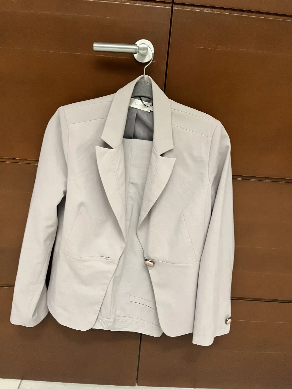 Traje sastrero de dos piezas color gris claro. Incluye blazer con un botón y pantalón de corte recto. Ideal para un look formal y elegante.