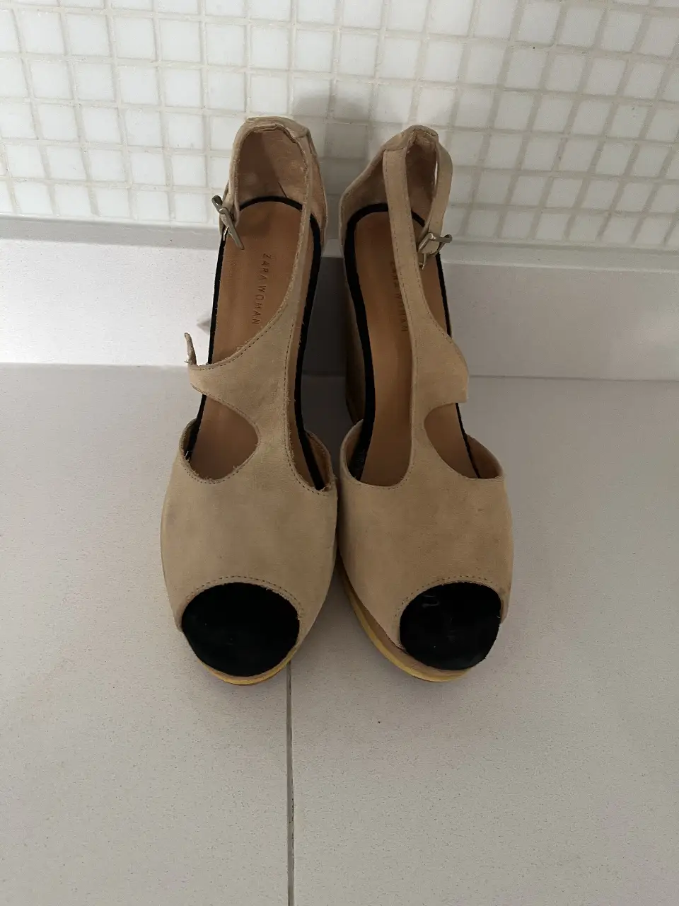 Sandalias de cuña de gamuza color crema con puntera negra. Ideales para un look elegante y cómodo.