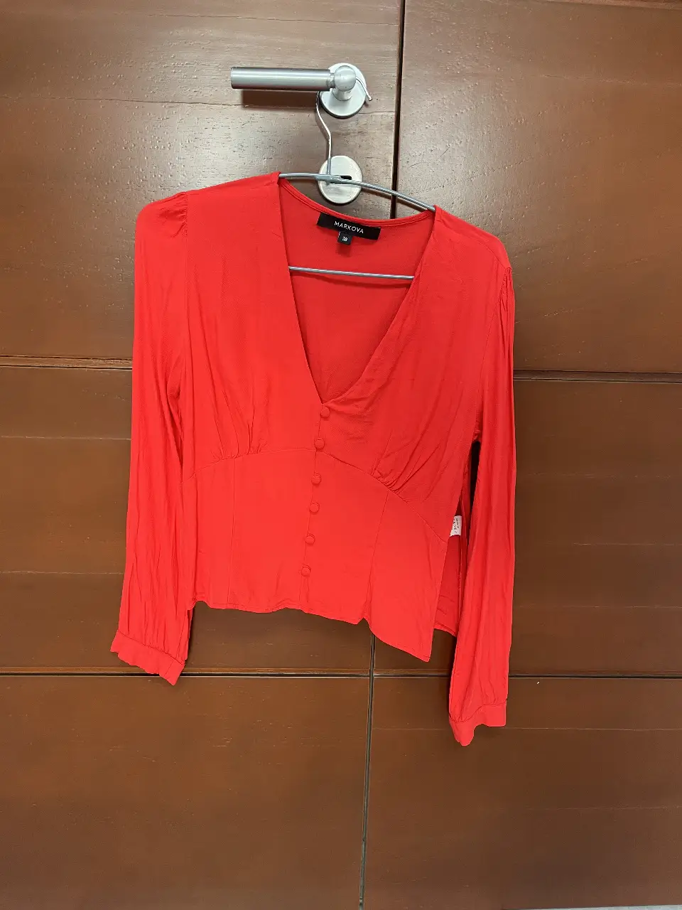 Blusa roja de manga larga con escote en V y botones frontales. Ideal para un look elegante y femenino.